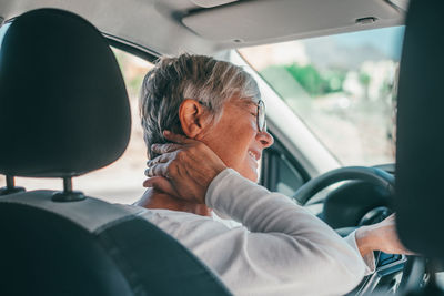 Senior woman with hurt neck in car