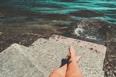 Low section of woman on rock by sea