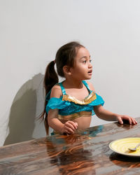 Little girl wearing arabian costume sitting at the table.