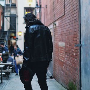 Rear view of man standing on brick wall