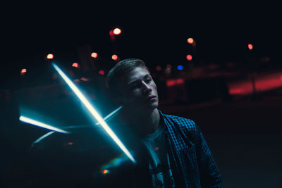 Full length portrait of young man with illuminated lights at night