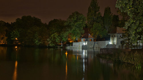 Scenic view of lake by trees against sky at night