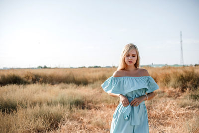 Teenage girl wearing dress standing on land against sky