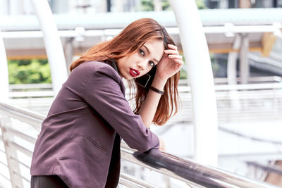 Portrait of thoughtful young businesswoman standing on elevated walkway 