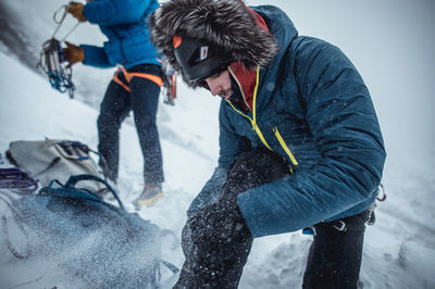 An ice climber adjusts his boots before a winter climb in maine