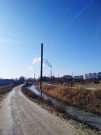 Road amidst field against clear sky