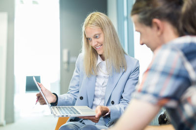 Young woman using laptop while sitting on table