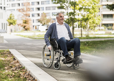 Smiling senior man in sweater sitting on wheelchair