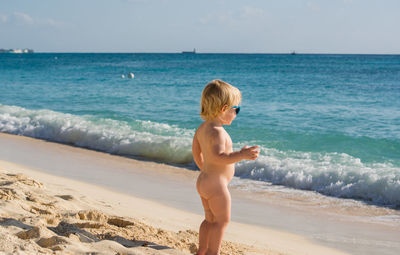 Full length of shirtless boy standing on beach