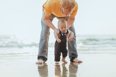 Full length of father and son at sea shore