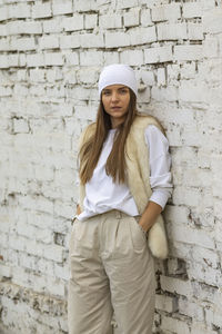 Portrait of smiling young woman standing against brick wall