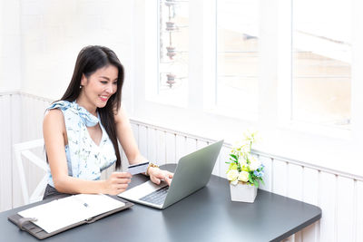 Young woman using phone while sitting on table
