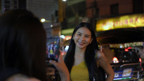 Portrait of smiling woman in illuminated city at night