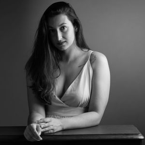 Portrait of young woman sitting against wall