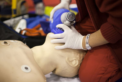 Midsection of man practicing on cpr dummy at hospital