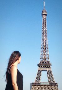 Woman standing by eiffel tower against sky