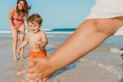 Parents playing with son on beach near sea