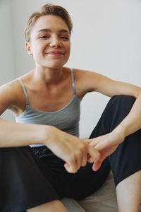 Portrait of young woman exercising against wall