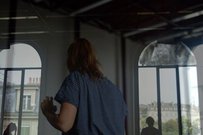 Rear view of woman standing by window