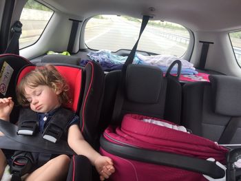 Cute girl sleeping on car during road trip