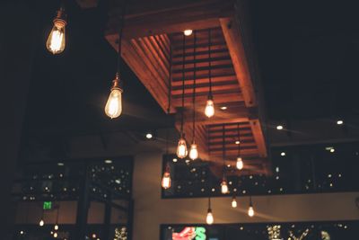 Low angle view of illuminated light bulbs hanging from ceiling