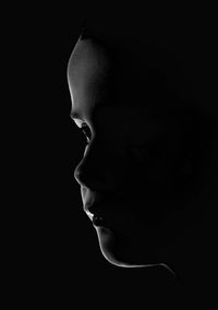 Close-up of young woman against black background