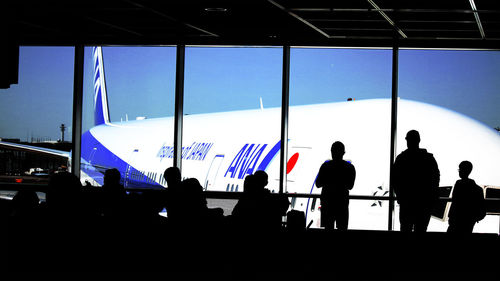 Silhouette people waiting at airport against sky