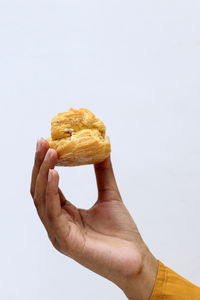 Cropped hand of person holding fruit against white background