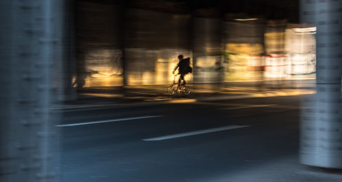 Blurred motion of man riding bicycle on road