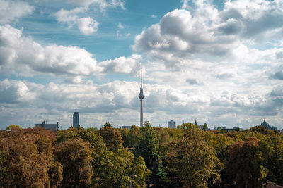 Plants growing in city against cloudy sky