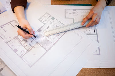 Midsection of architect working on blueprint