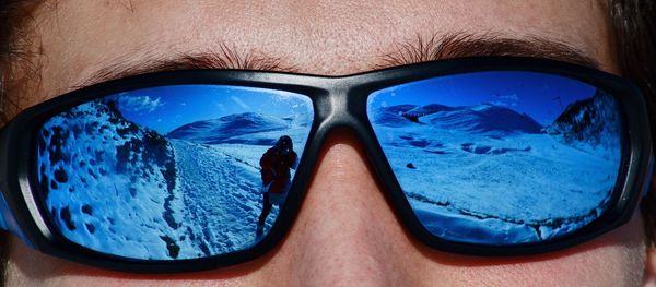 Reflection of man on sunglasses against blue sky
