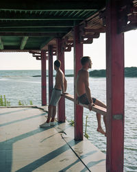 Rear view of friends standing on pier over sea