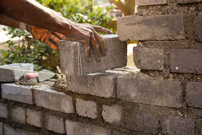 Close-up of hand holding bricks and laying wall