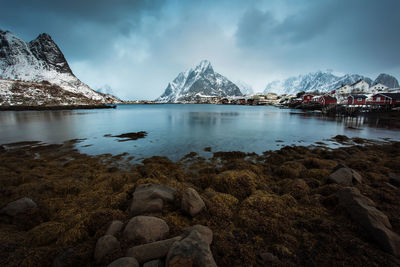 Scenic view of lake by snowcapped mountains against sky