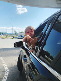 Portrait of smiling young kid in  black car