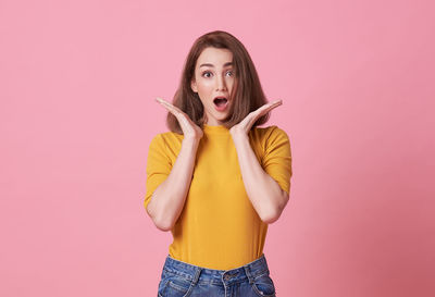 Portrait of young woman standing against colored background