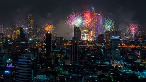 Firework display over illuminated buildings in city at night