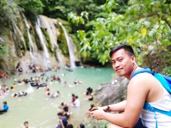 Portrait of man against waterfall in forest