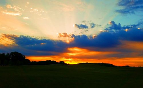 Scenic view of dramatic sky over land during sunset