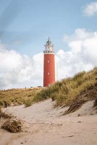 Lighthouse on beach against sky