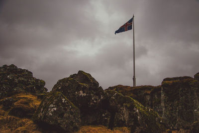 Low angle view of flag on rock against sky