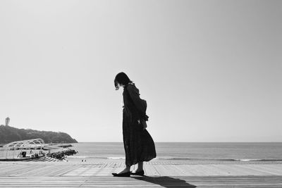 Woman standing on beach against clear sky