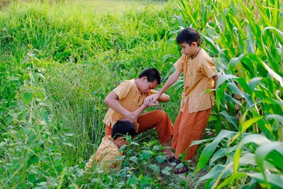 Boys assisting friend in climbing on hill