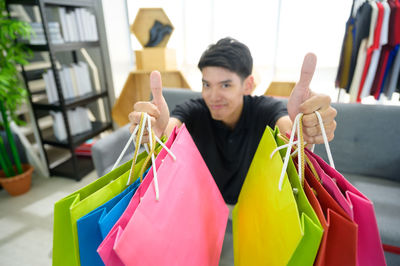 Portrait of teenage boy holding multi colored store