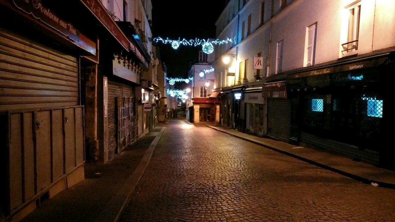 ILLUMINATED ROAD AMIDST BUILDINGS IN CITY