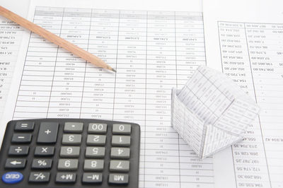 Calculator and model house on financial documents at desk