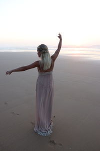 Rear view of woman at beach during sunset