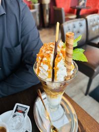 Midsection of an ice cream in a large glass with whipped cream and caramel sauce