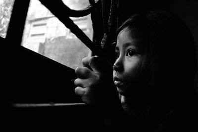 Close-up portrait of girl looking through window at home